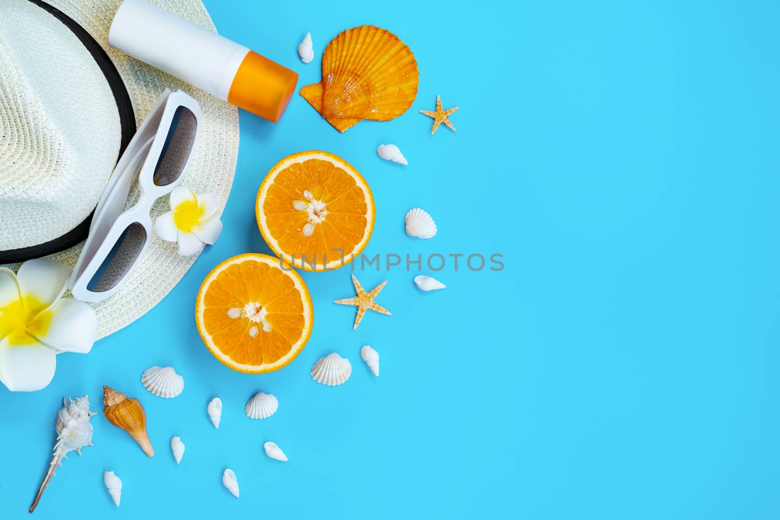 Beautiful summer holiday, Beach accessories, sunglasses, hat, orange, sunblock and shells on blue backgrounds