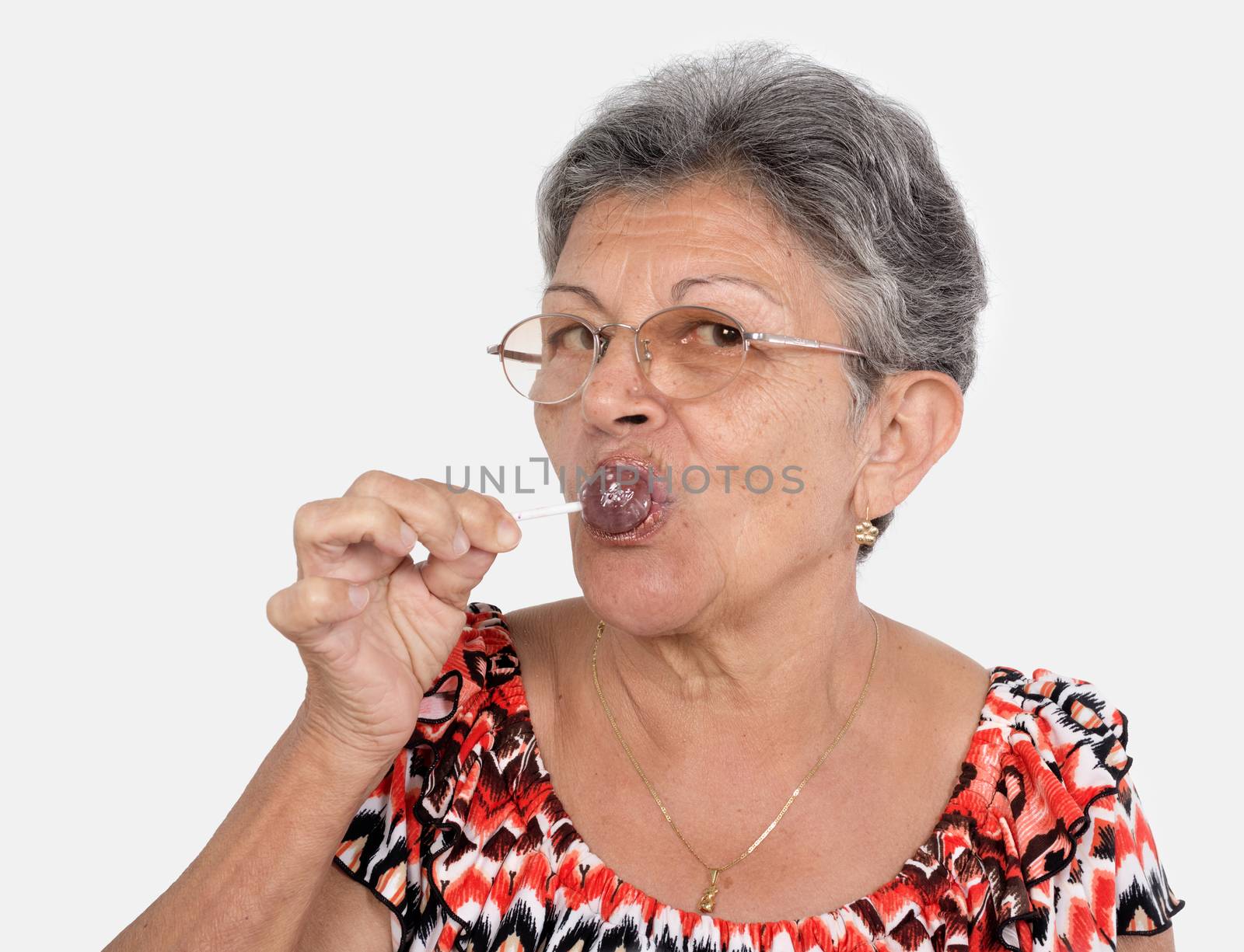 An old woman wearing glasses with a candy in her mouse