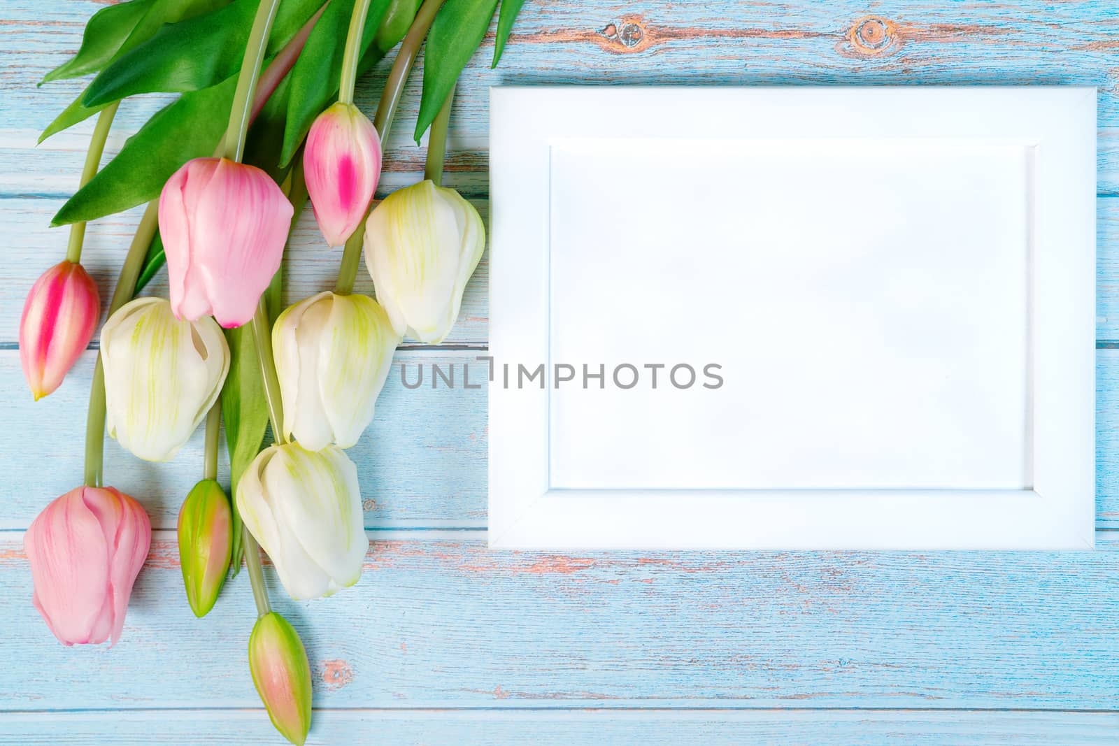 white picture frame and flower on wooden table background