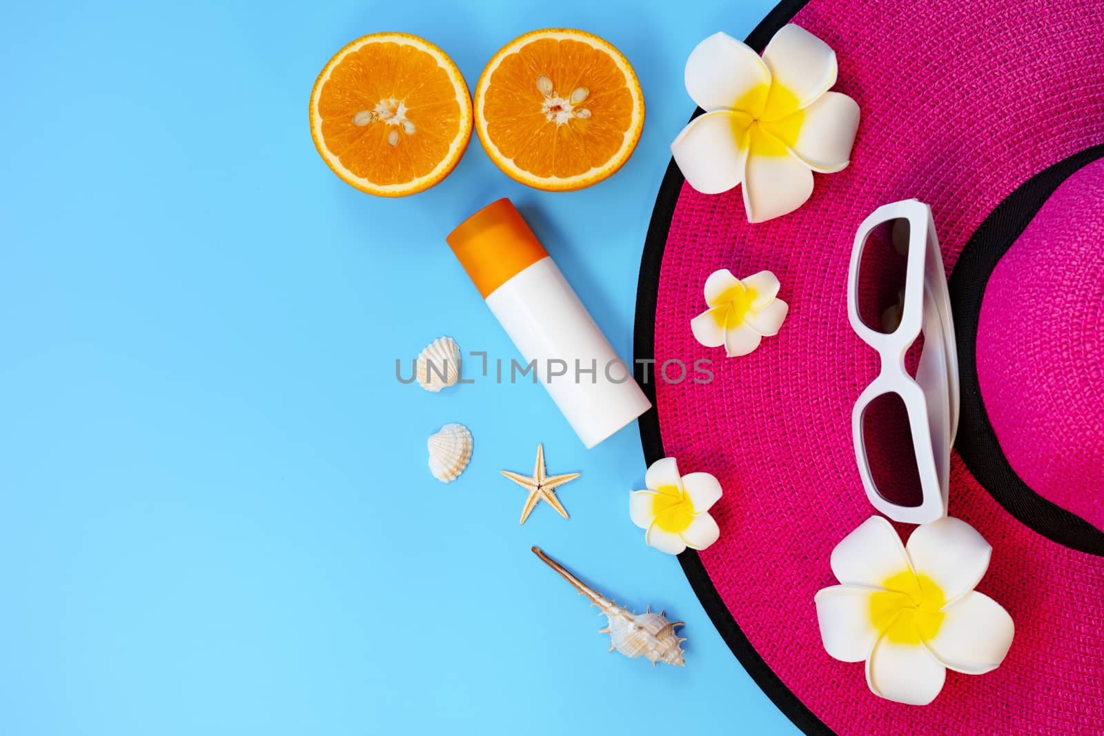 Beautiful summer holiday, Beach accessories, sunglasses, hat, orange, sunblock and shells on blue backgrounds