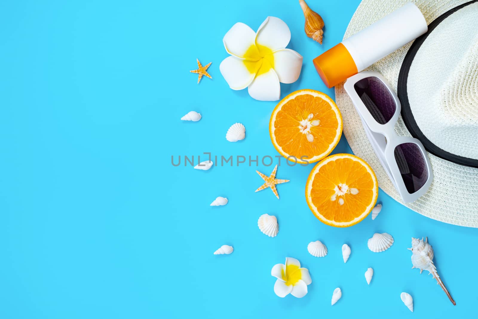 Beautiful summer holiday, Beach accessories, sunglasses, hat, orange, sunblock and shells on blue backgrounds