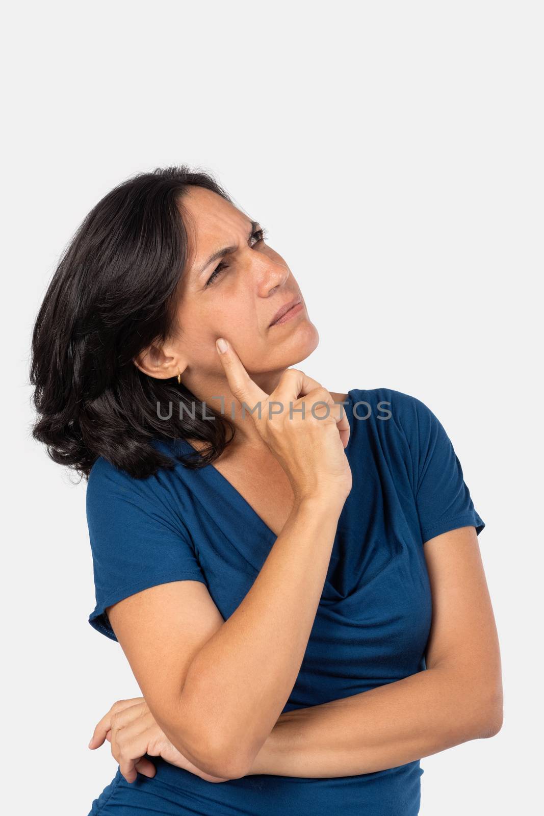 A woman thinking,with one finger touching her face, she is wearing a blue blouse