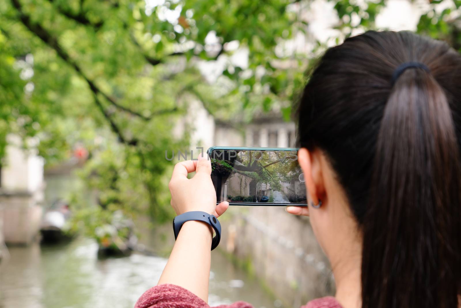 young woman having fun in local canal city in China with camera on smartphone making pictures
