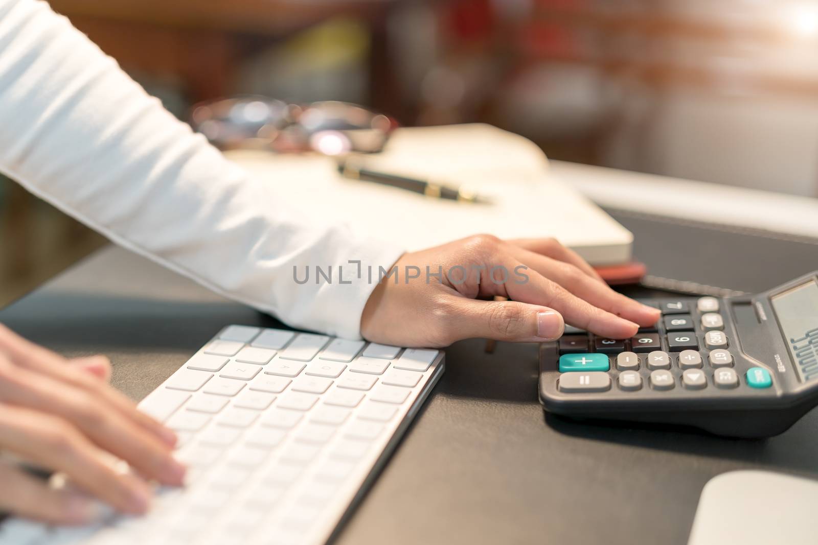 young business women typing on calculator at office - filter applied