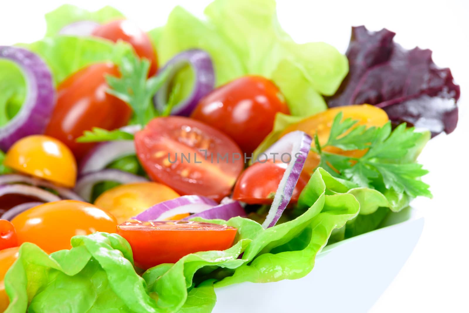 Fresh mixed vegetable salad in a bowl on a white background.