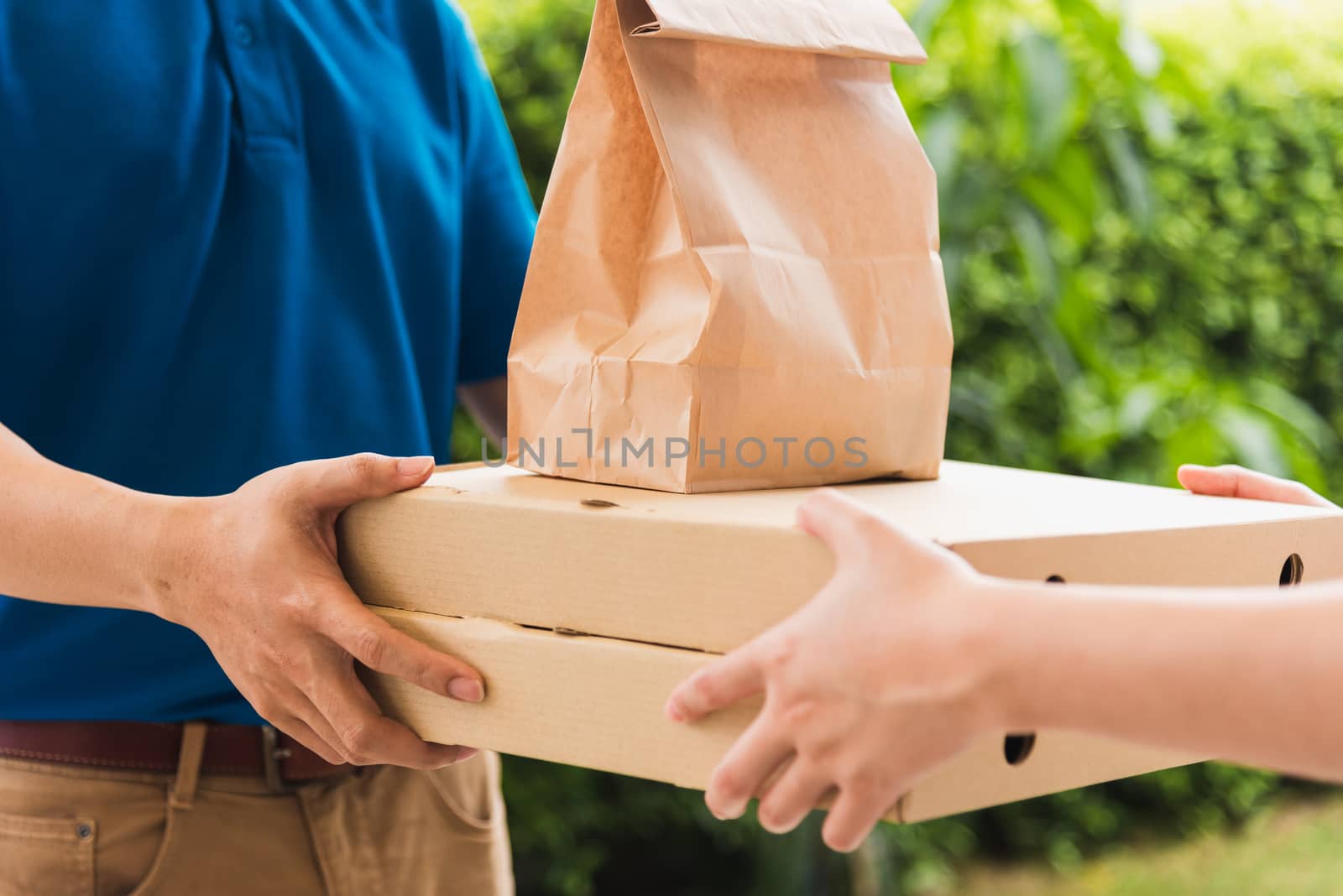 Asian delivery express courier young man giving paper bags fast food and pizza box to woman customer receiving both protective face mask, under curfew quarantine pandemic coronavirus COVID-19