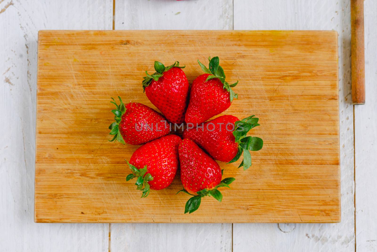 Organic strawberries in a circle on a cutting board fruit on a white wooden table