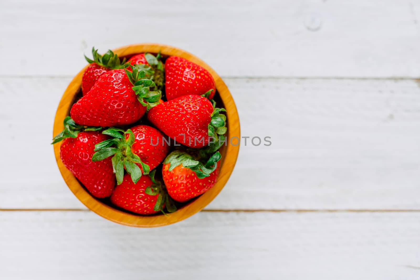 Organic strawberries on a bowl on a white wooden table much colorful