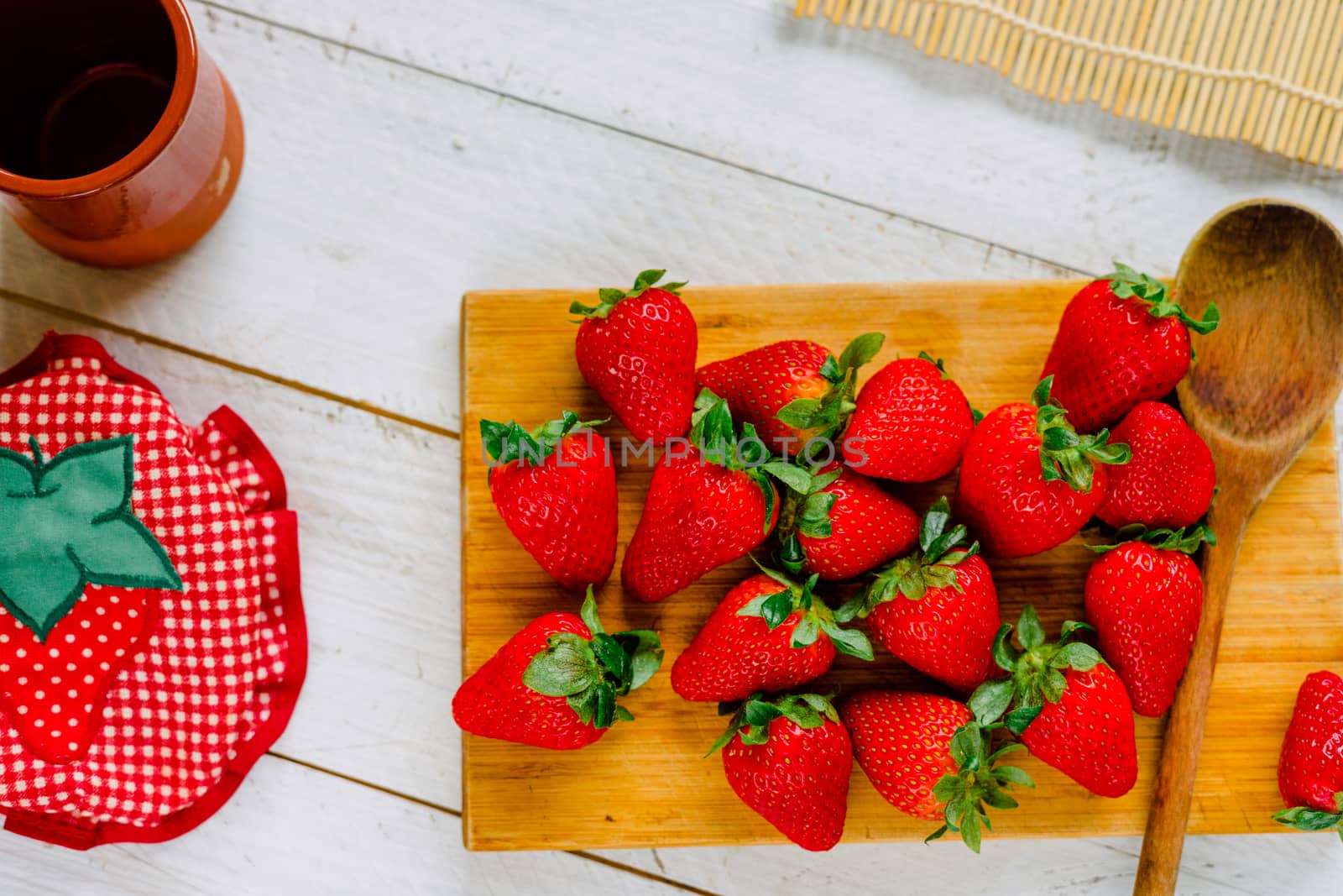 Organic strawberries on a cutting board fruit on a white wooden table