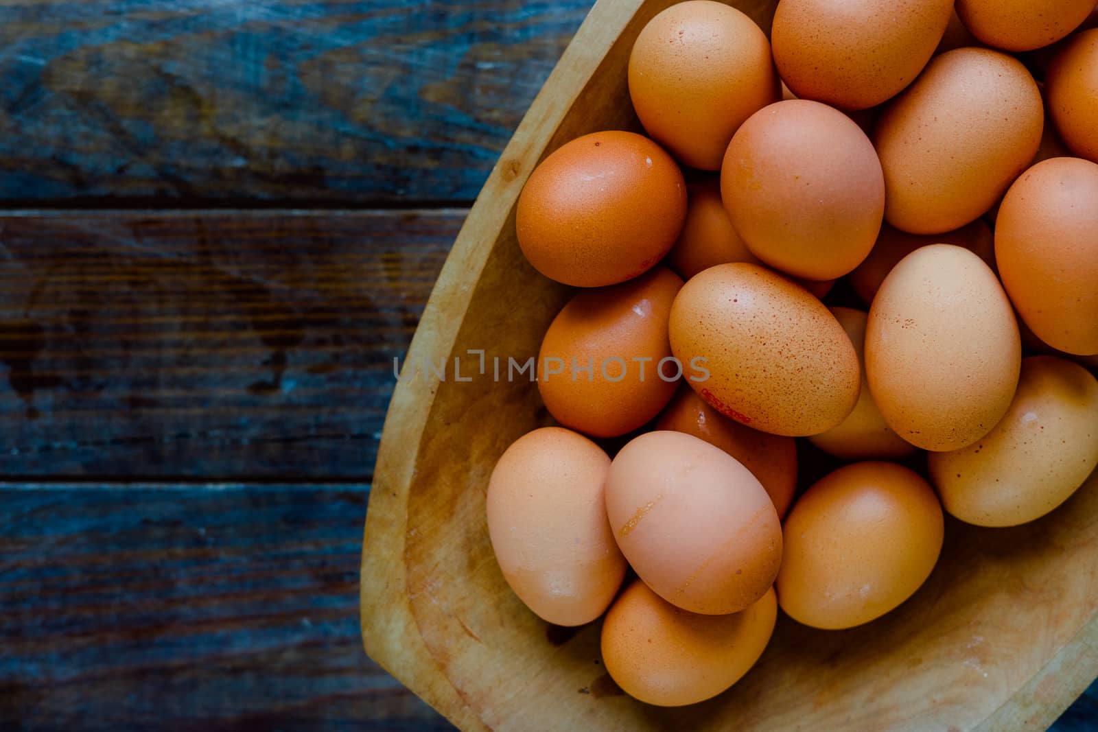 Organic eggs in a large wooden bowl on a wooden table