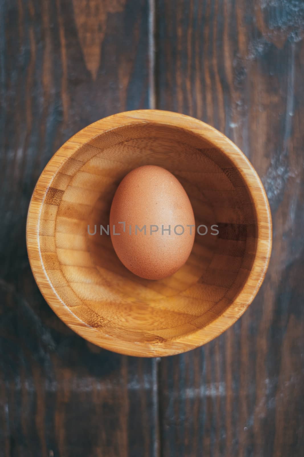 Organic egg in a wooden bowl on a wooden table