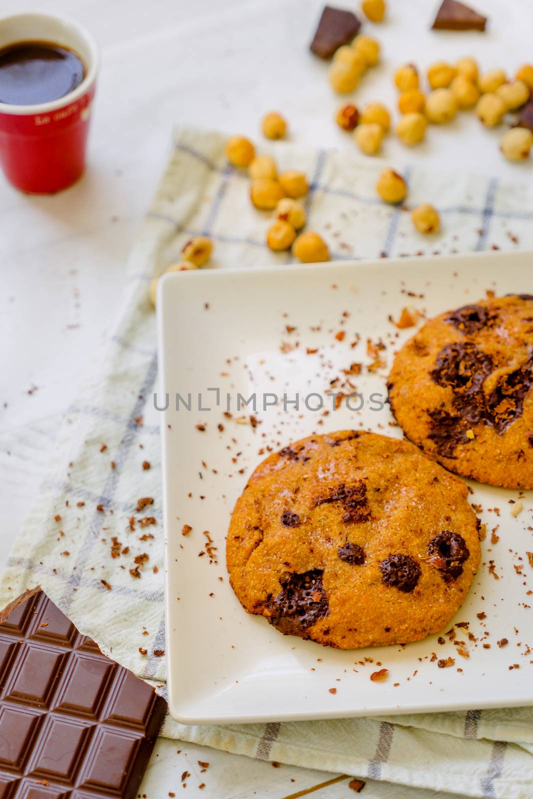 Organic chocolate chip cookies with hazelnuts and coffee in a square plate on a wooden table