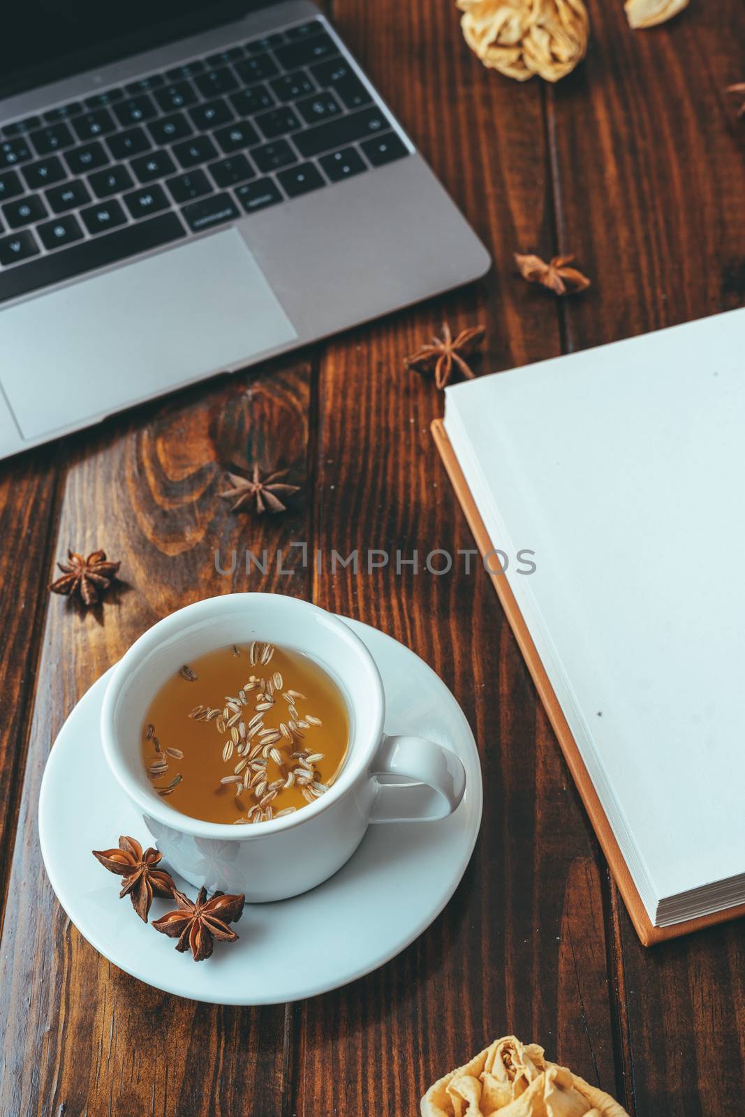 Laptop, cup of tea and notebook on a wooden table by Dumblinfilms