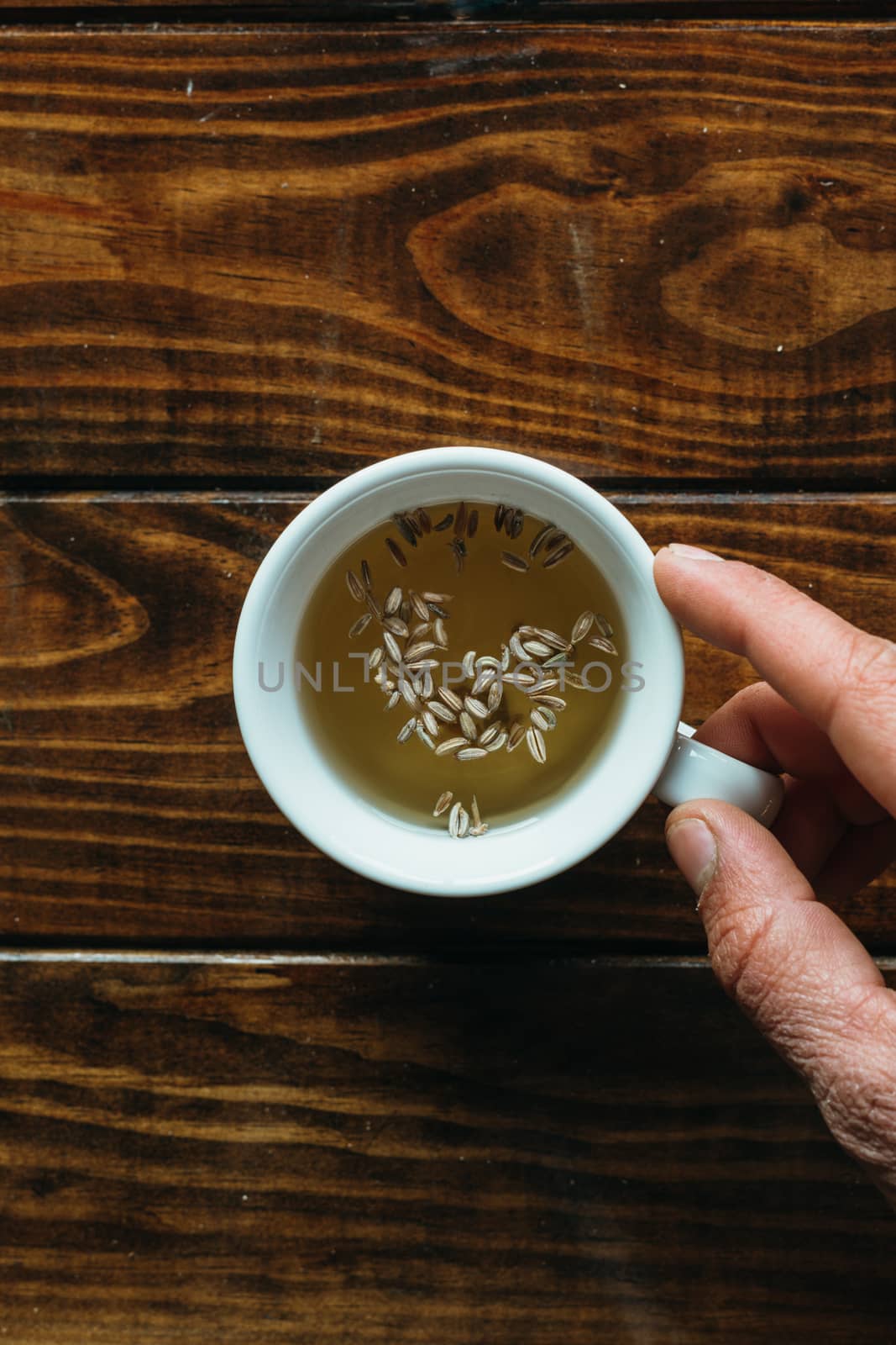 white cup of tea with one hand on a wooden table