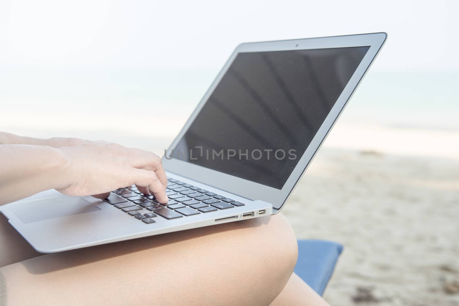 Woman sitting print with a laptop at the beach.