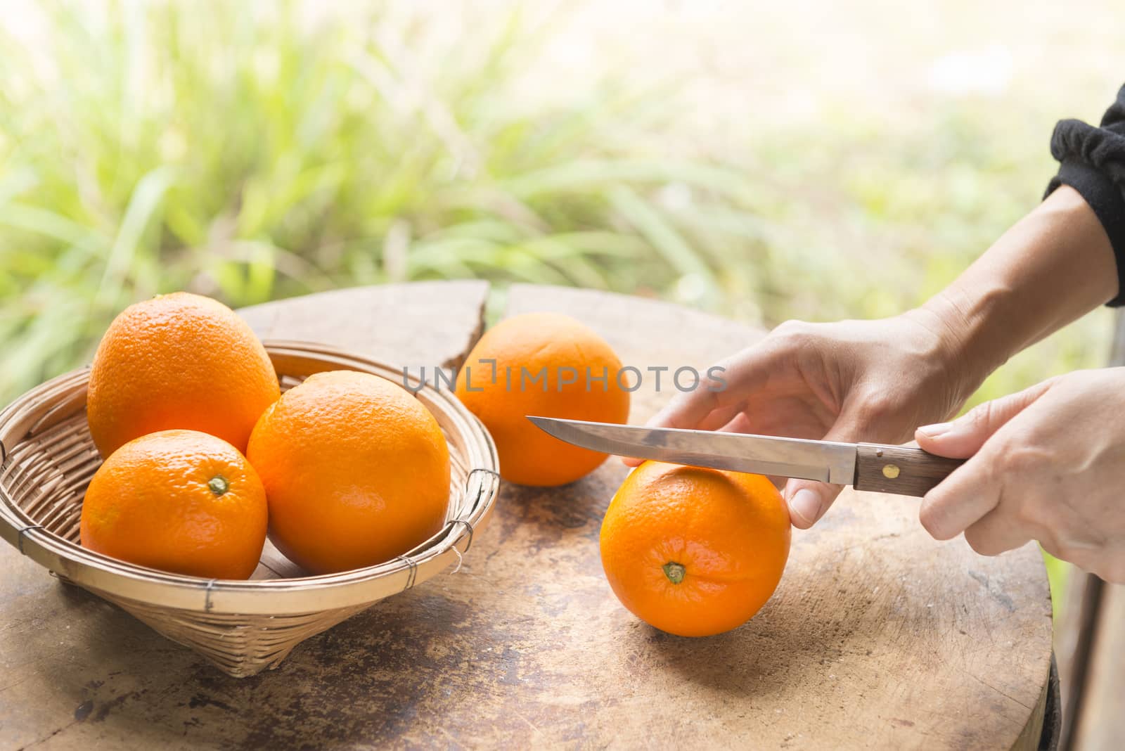 Woman cut orange on wooden table prepared to make orange juice.