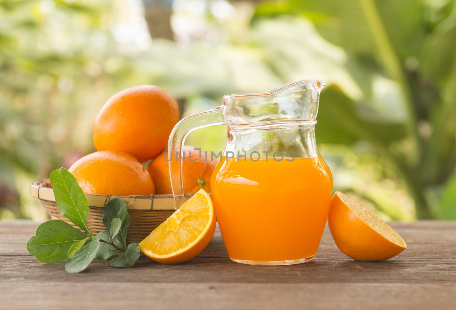 Orange juice is placed on a wooden table with natural light.