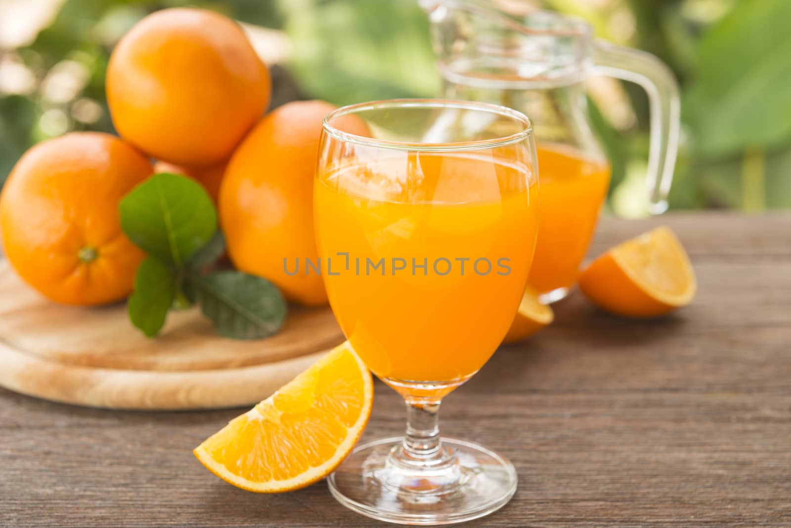 Orange juice is placed on a wooden table with natural light.