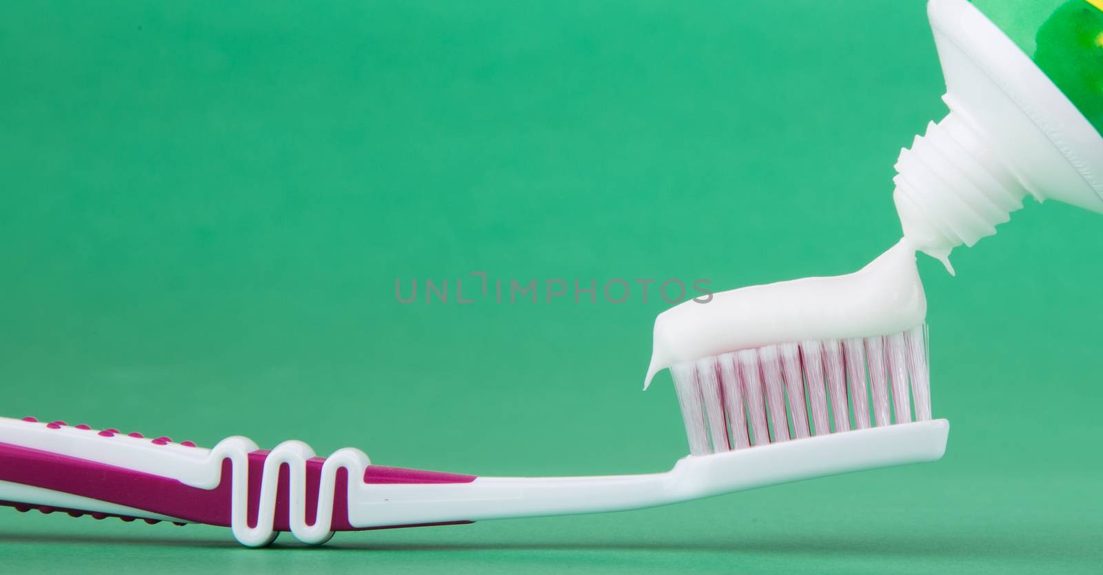 toothbrush with toothpaste isolated on a green background