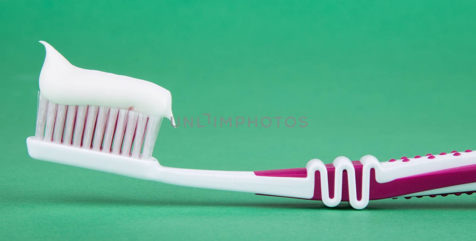 toothbrush with toothpaste isolated on a green background