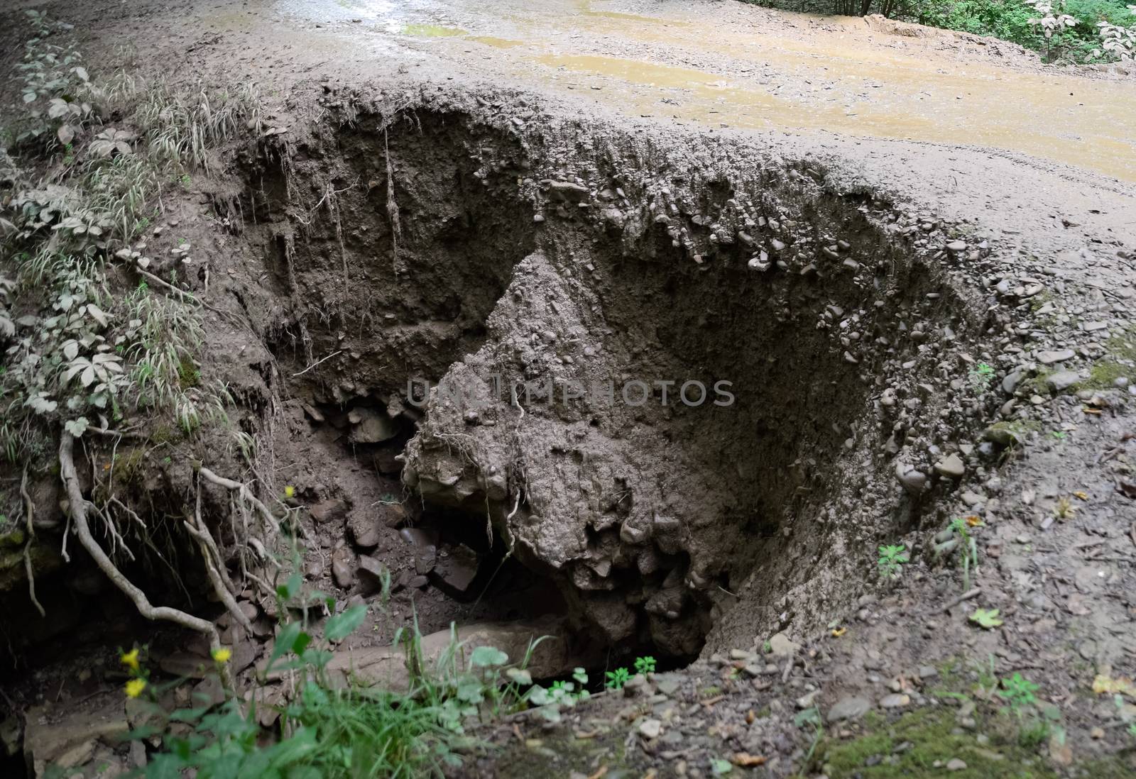 The collapsed edge of the road from the rain. Akyduct for water runoff.