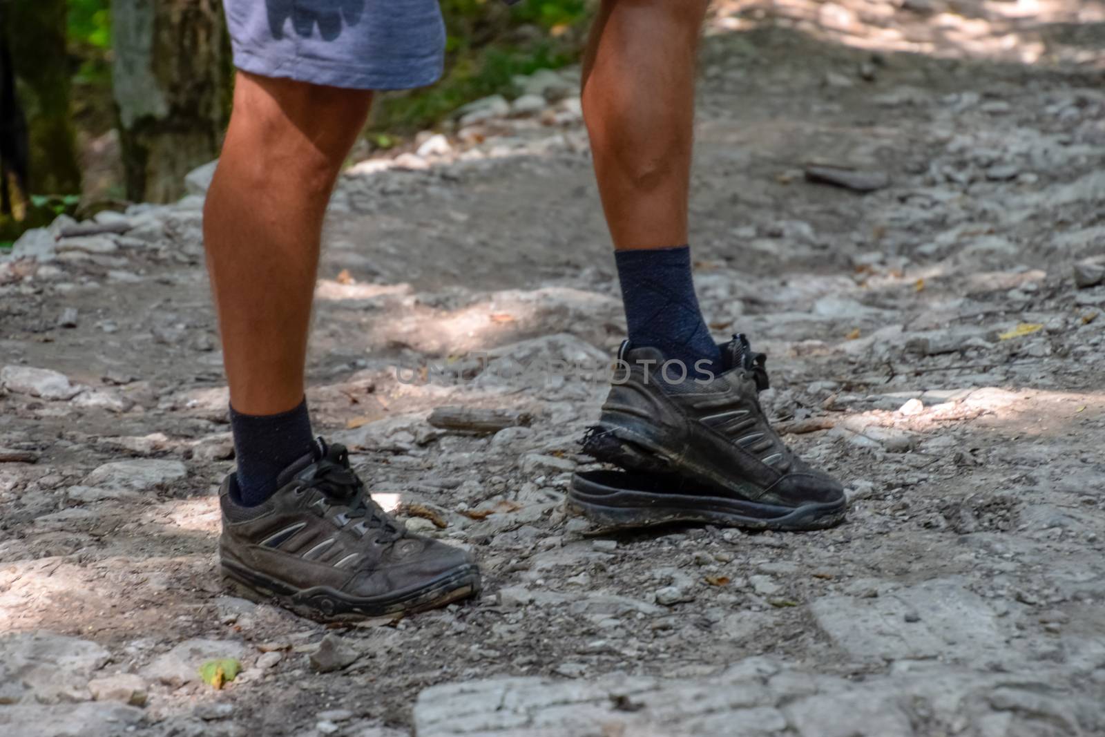 The detached sole on the tourist's sneakers. They broke their boots in the woods.