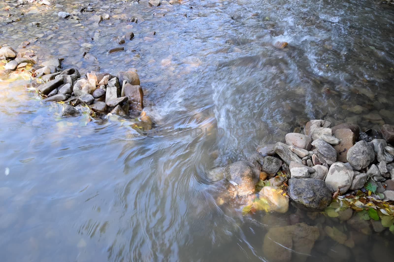 The flow of water on the doorstep in a mountain river. A shallow mountain river, the bottom of a mountain river of stones and gravel.