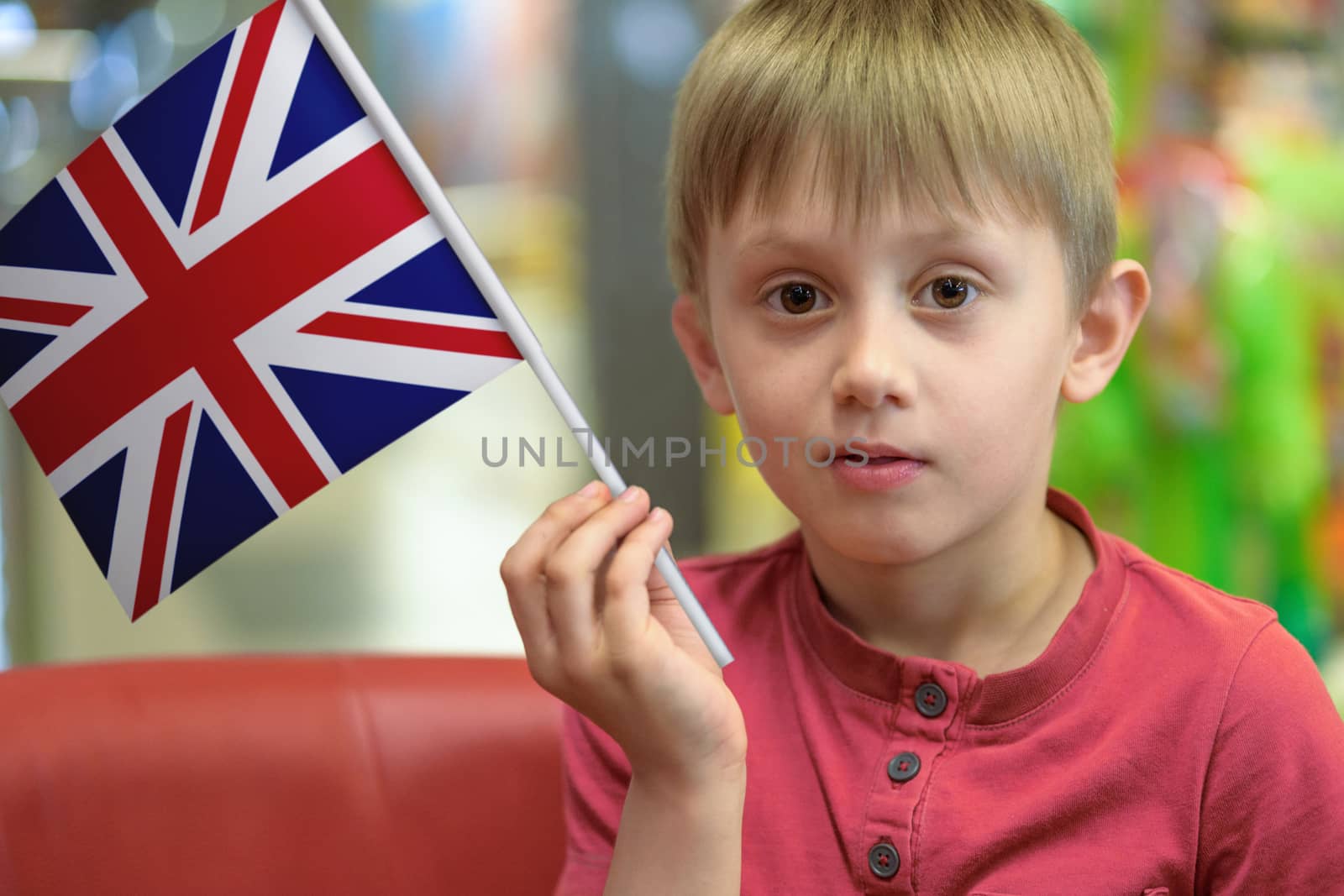 Little boy as a patriot holding in his hand a  paper flag of The United Kingdom.
