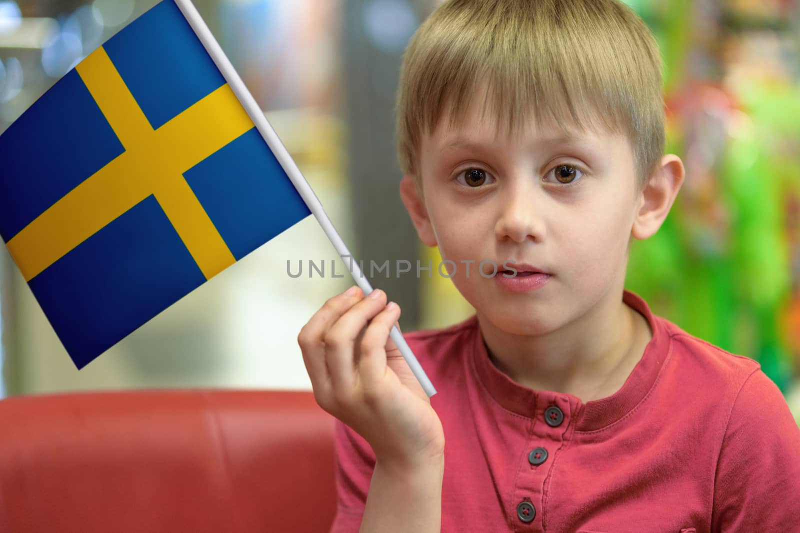 Little boy as a patriot holding in his hand a  paper flag of Sweden