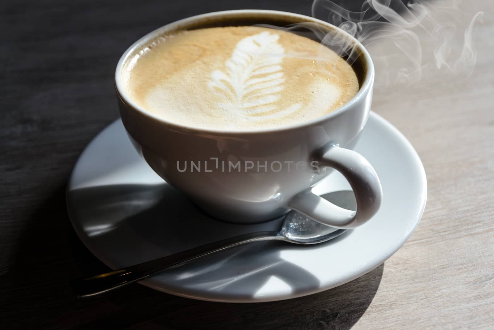 Closeup of a white cup of hot cappuccino coffee on a restaurant table.