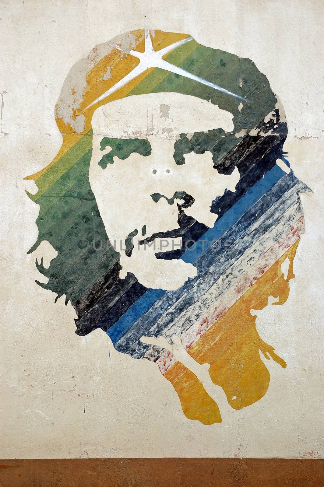 A wall painted with a colourful mural of the Cuban revolutionary leader Che Guevara. The image over looks a car park in Old Havana.