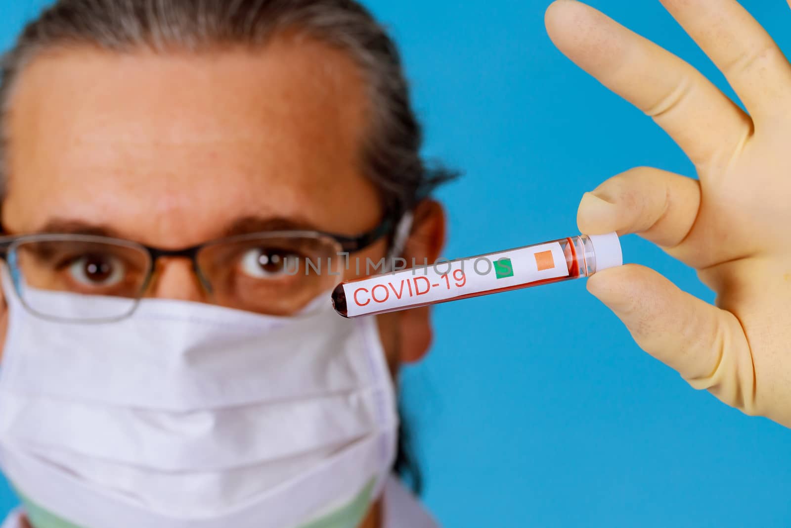 Coronavirus Covid 19 infected blood sample in sample tube in hand of doctor in face mask