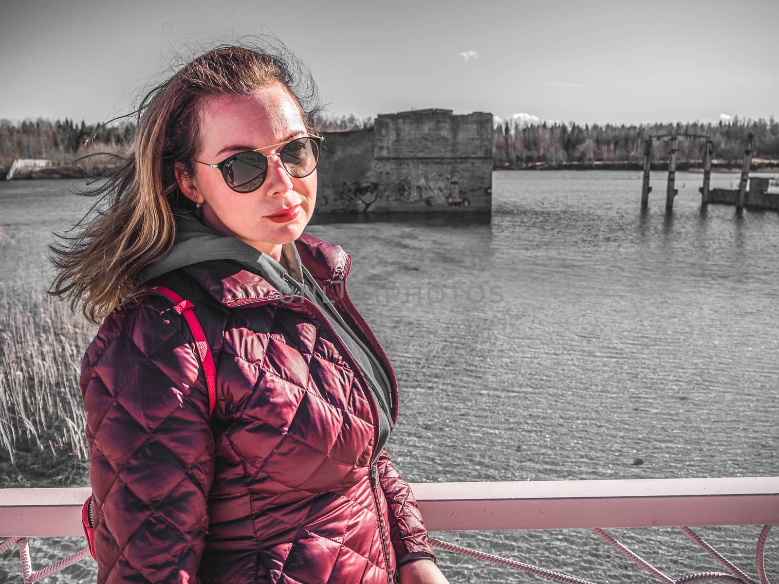 young woman with red jacket and abndoned Quarry Of Rummu, Estonia on the background. Scenic View Of Land Against Clear Blue Sky. Panoramic View.