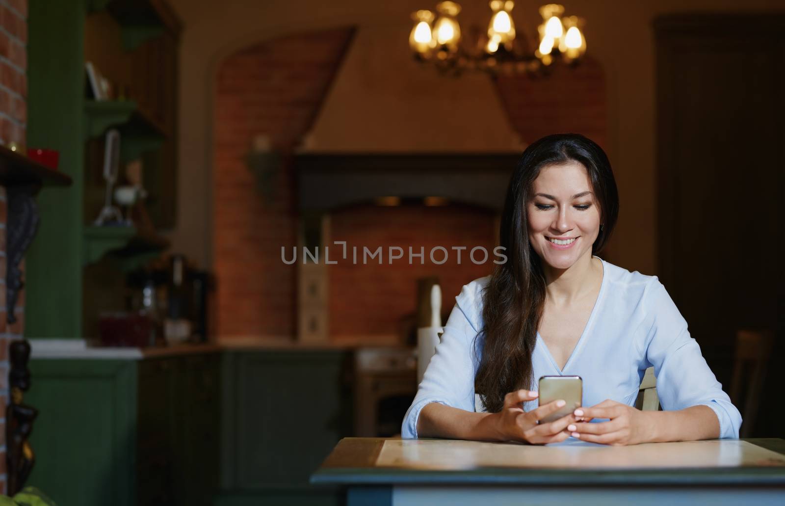 Smiling woman sitting and table and using smartphone by Novic