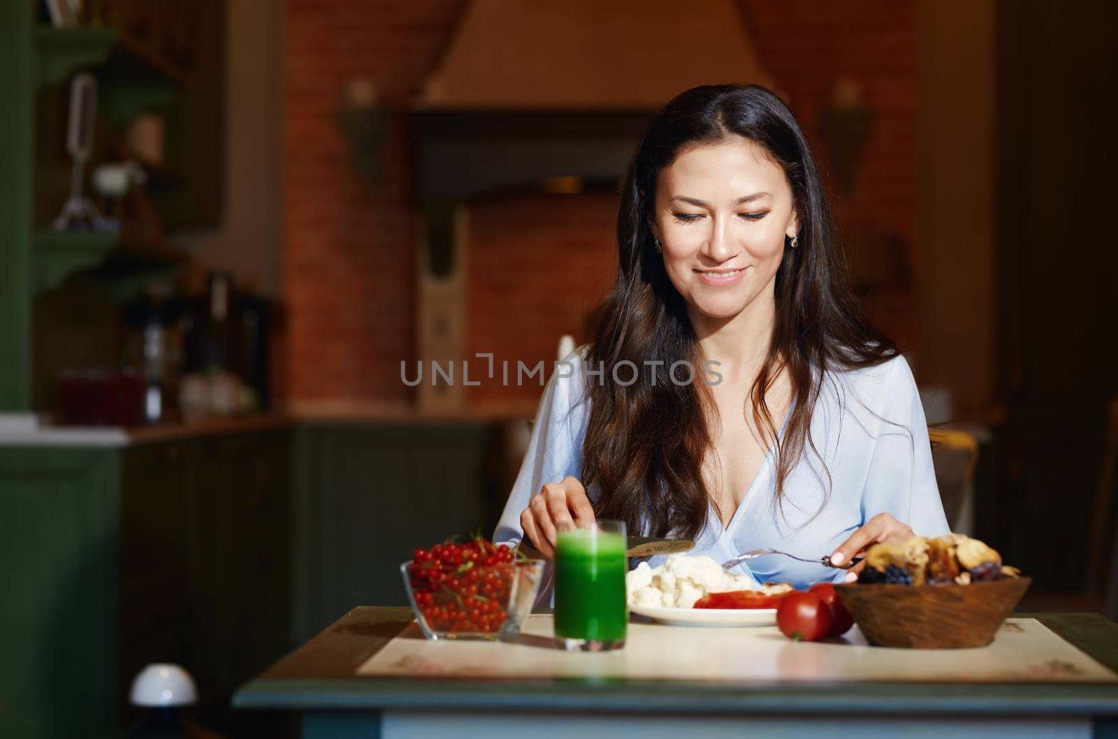 Smiling vegetarian woman sitting at the table and eating healthy food