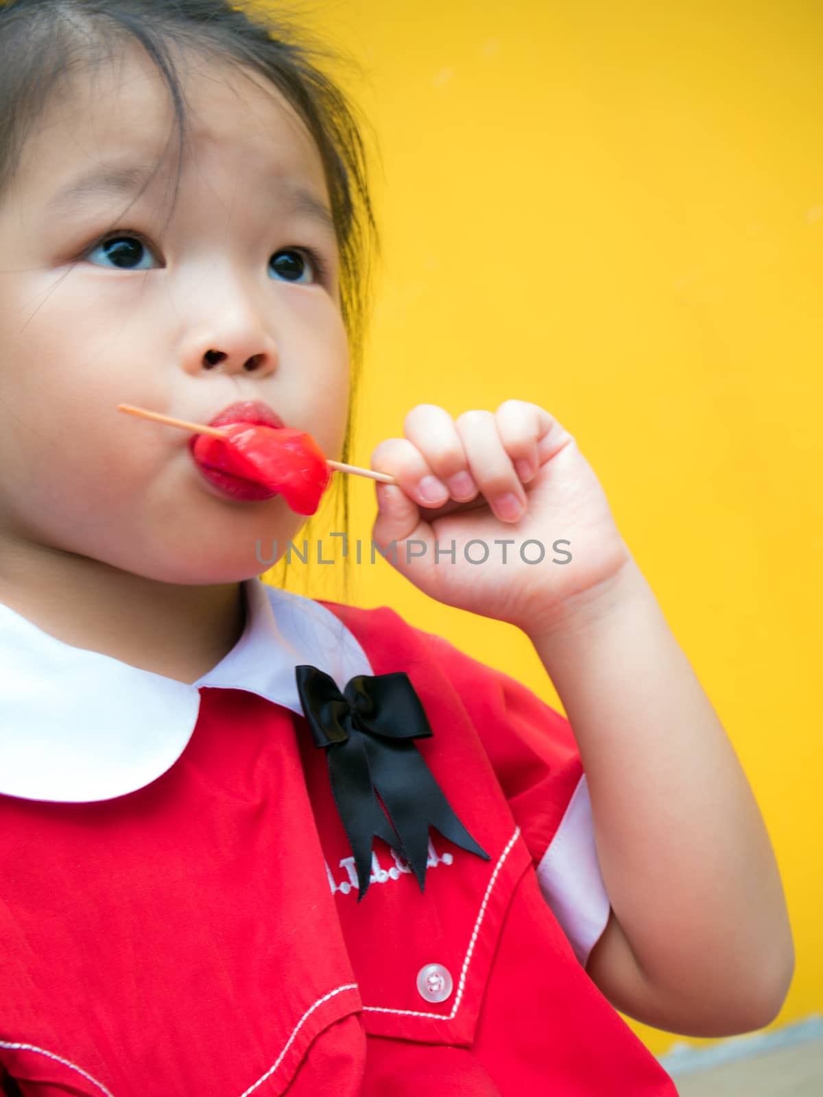 Little girls in red student dressed Eating a red popsicle