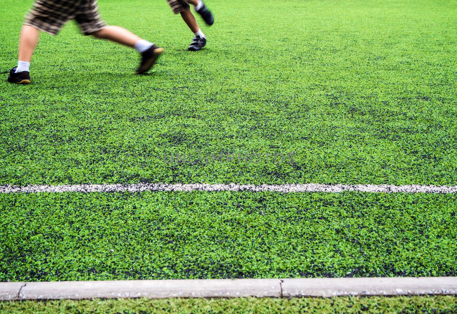 Children play on the artificial turf of the school by Satakorn