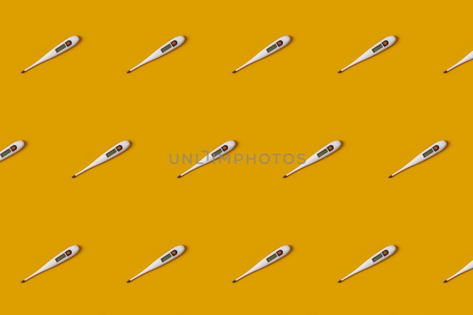 Digital electronic thermometer on the yellow colored background to cover on a yellow background. Epidemic concept. Regular pattern, flat lay.