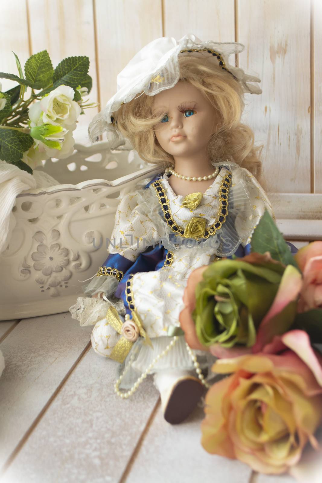 Antique porcelain doll in victorian style. Doll with clothes and pastel roses. Vertical image, shabby background