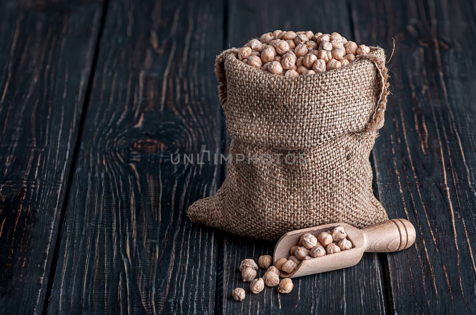 Chickpea in sack and scoop near on wooden table