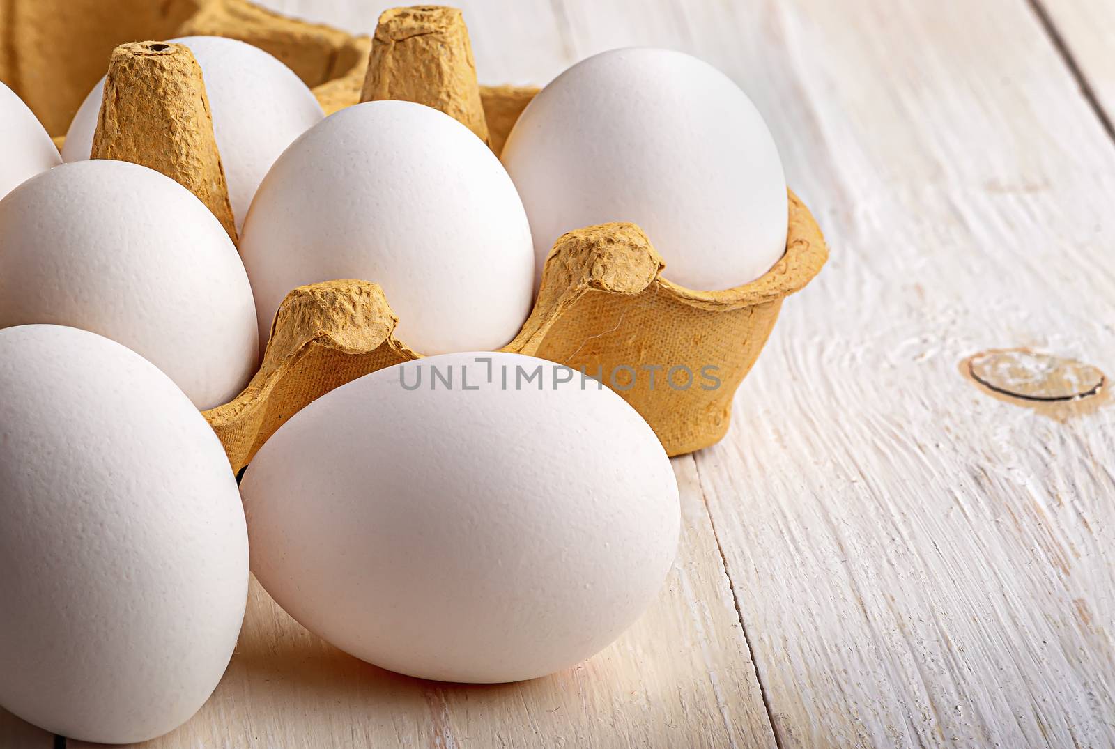 White eggs near paper tray on white table closeup