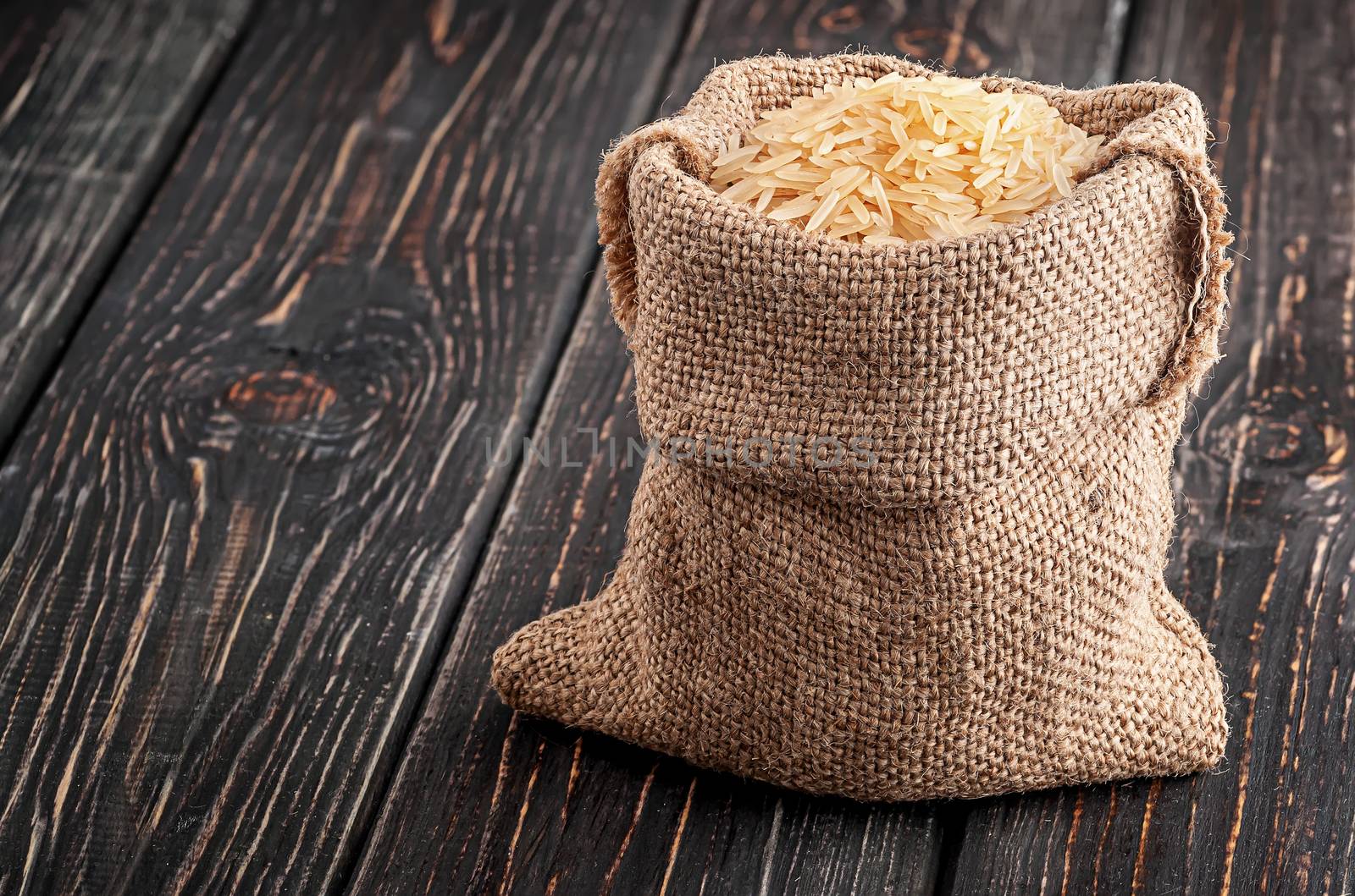Sack of long rice stands on wooden background