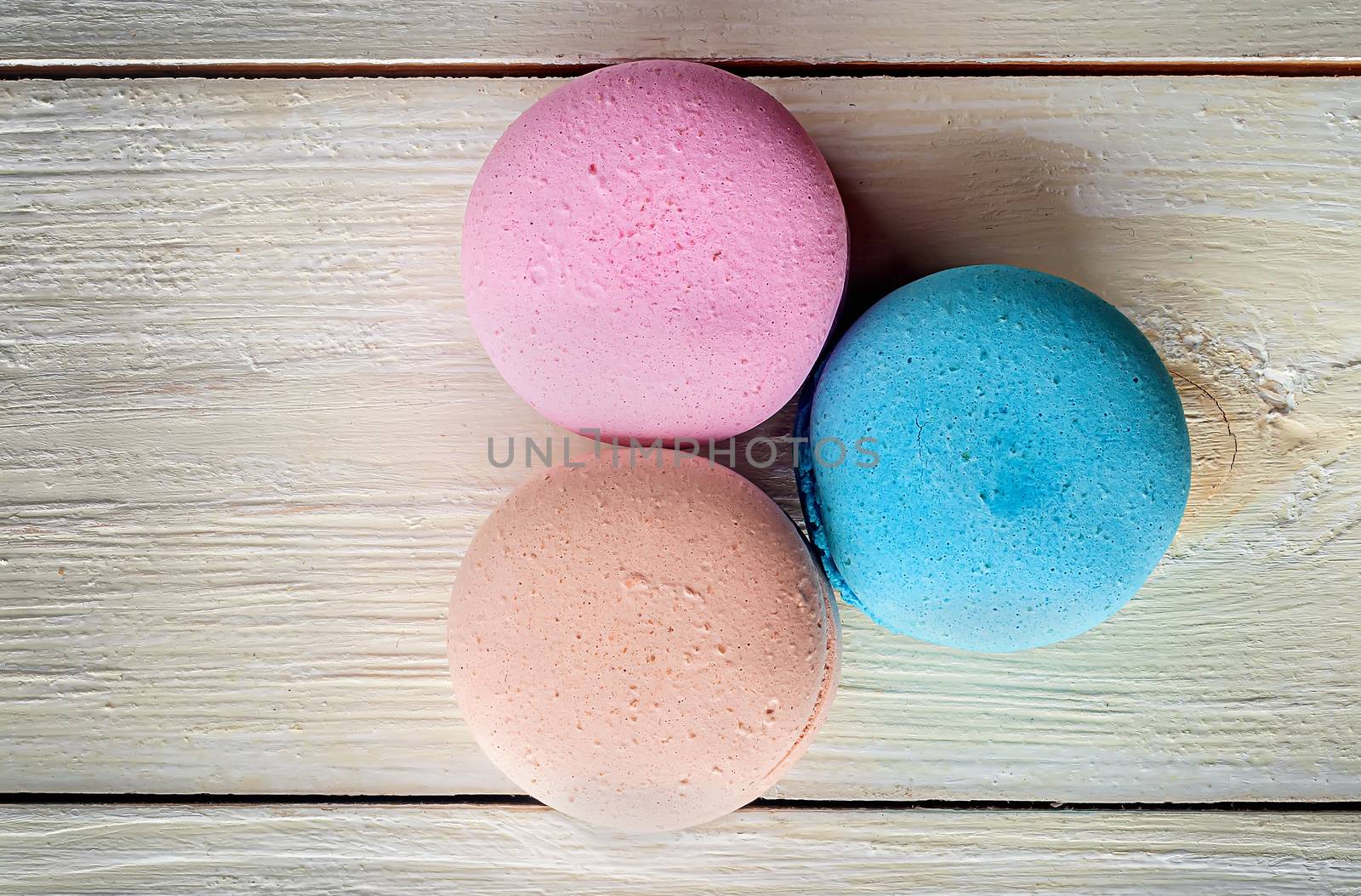 Three macaroons near on a wooden background top view