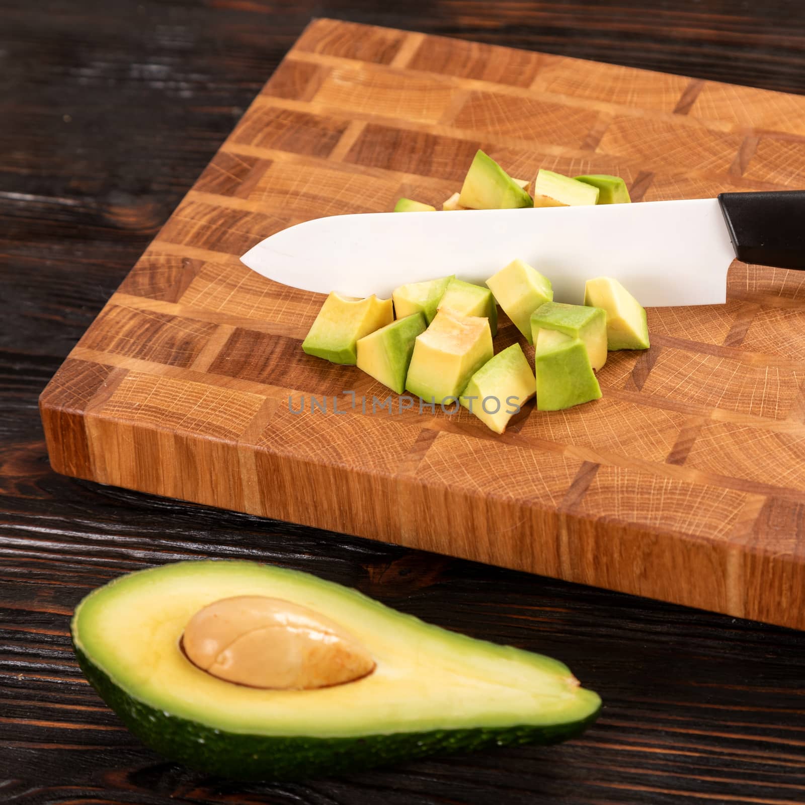 Avocado sliced with cube using knife on wooden cutting board