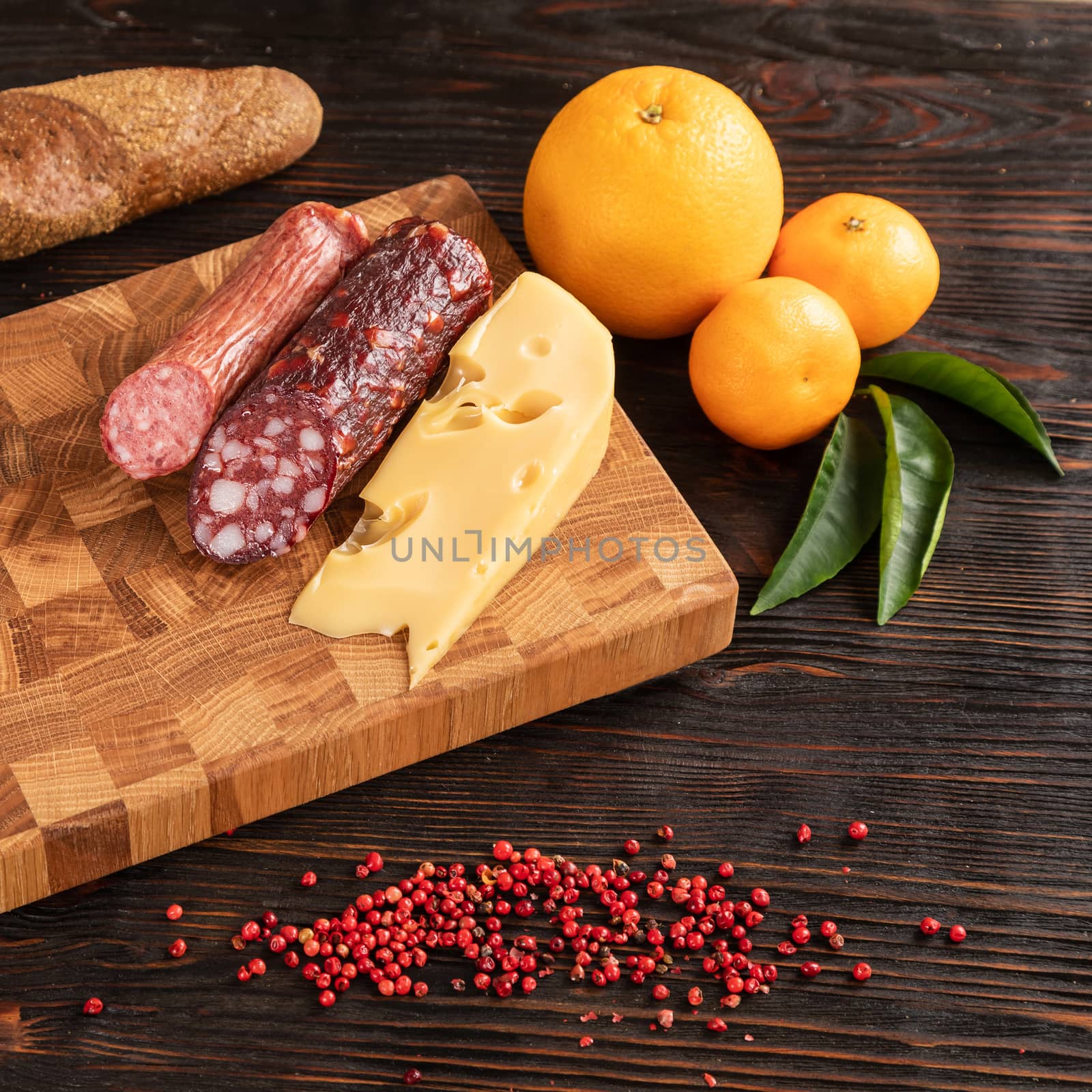 Sausage, cheese and bread on wooden cutting board