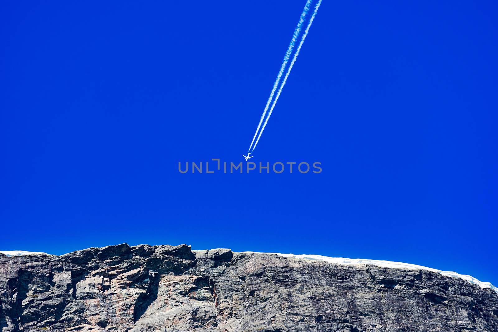 Airplane trail in the blue sky over mountain