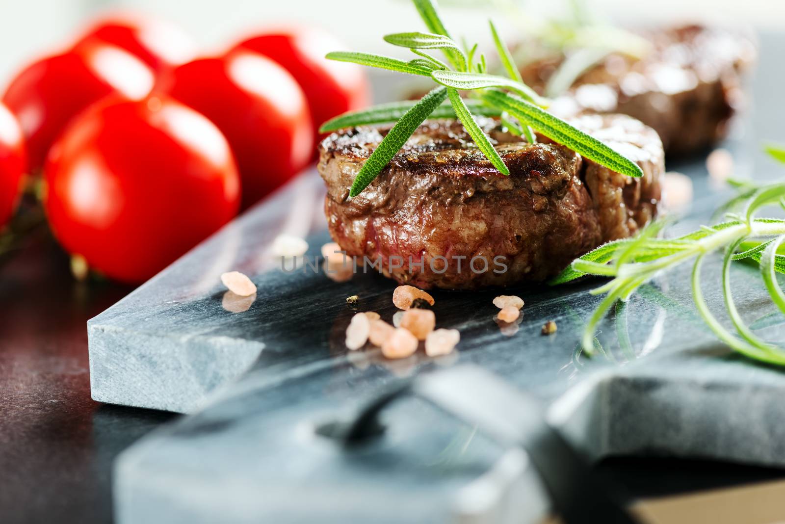 Beef steak with rosemary on marble cutting board.