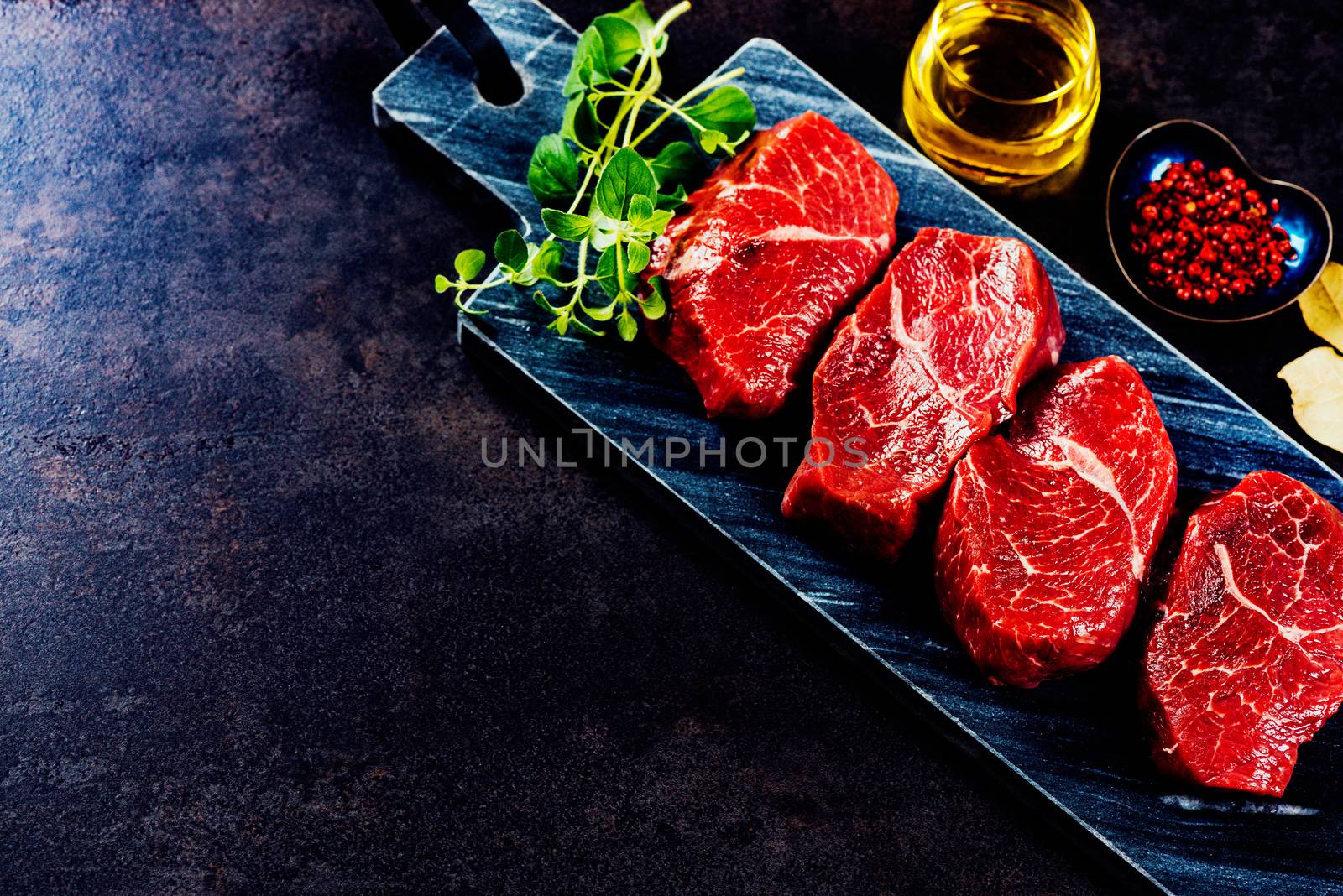 Beef steaks on cutting board with herbs and spices