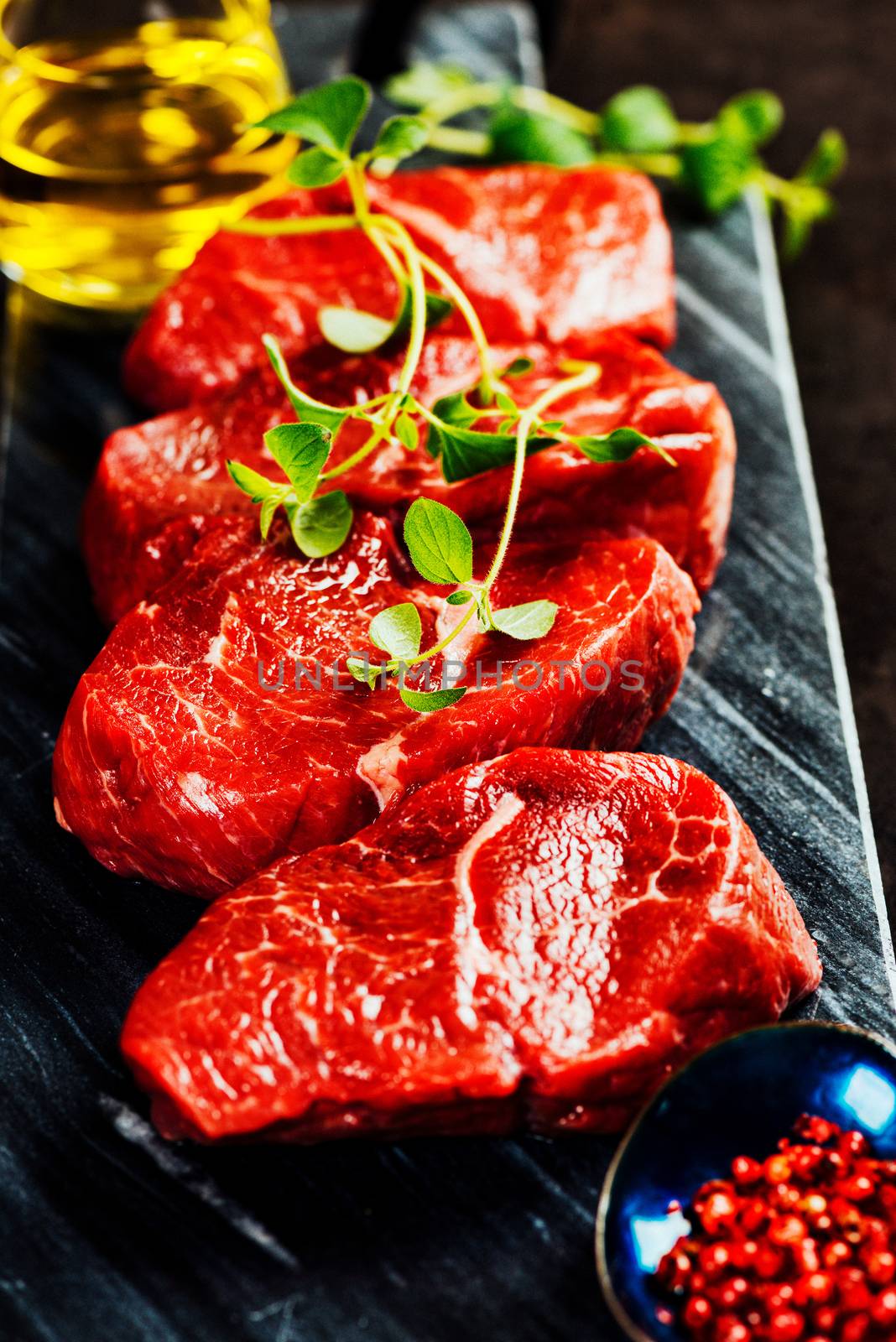 Beef steaks on cutting board with herbs and spices