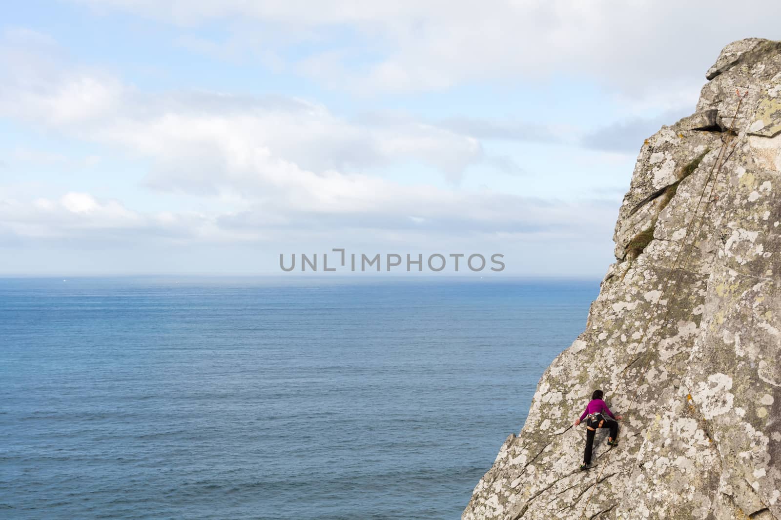 Woman climbing in front of the sea by JRPazos